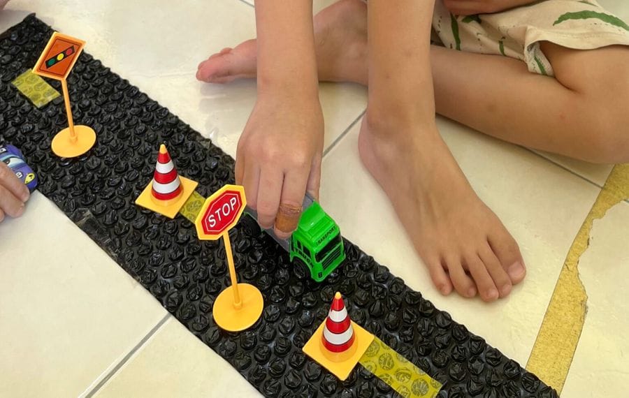 A child driving a toy truck along a road safety mat